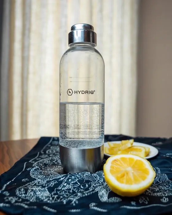 Botella de agua con gas y limones